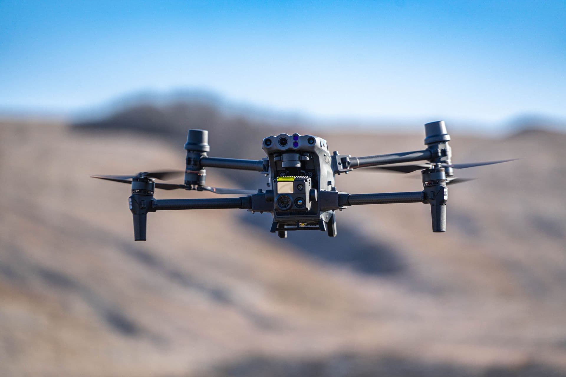 A commercial drone in flight against a blue sky, representing the US drone industry affected by new tariffs