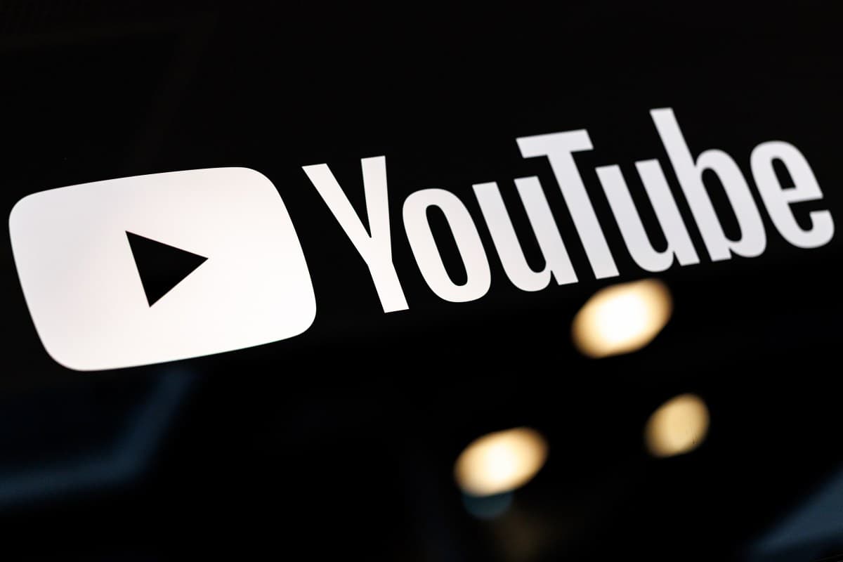 YouTube logo on a screen with a creator dashboard showing watch time metrics and monetization status