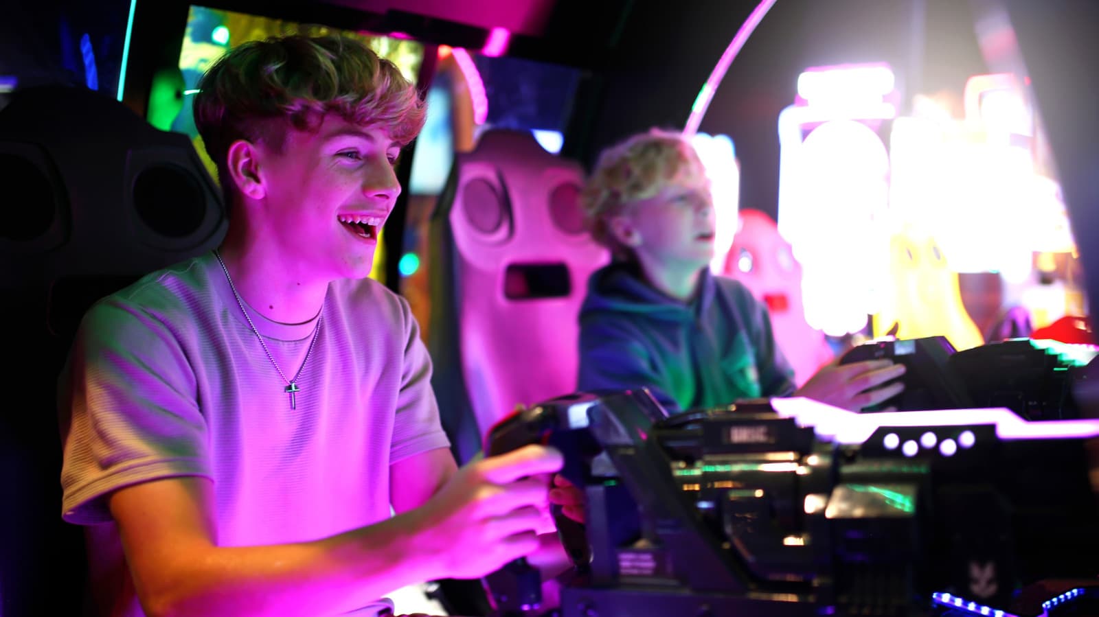 Young people playing classic arcade machines in a neon-lit retro venue