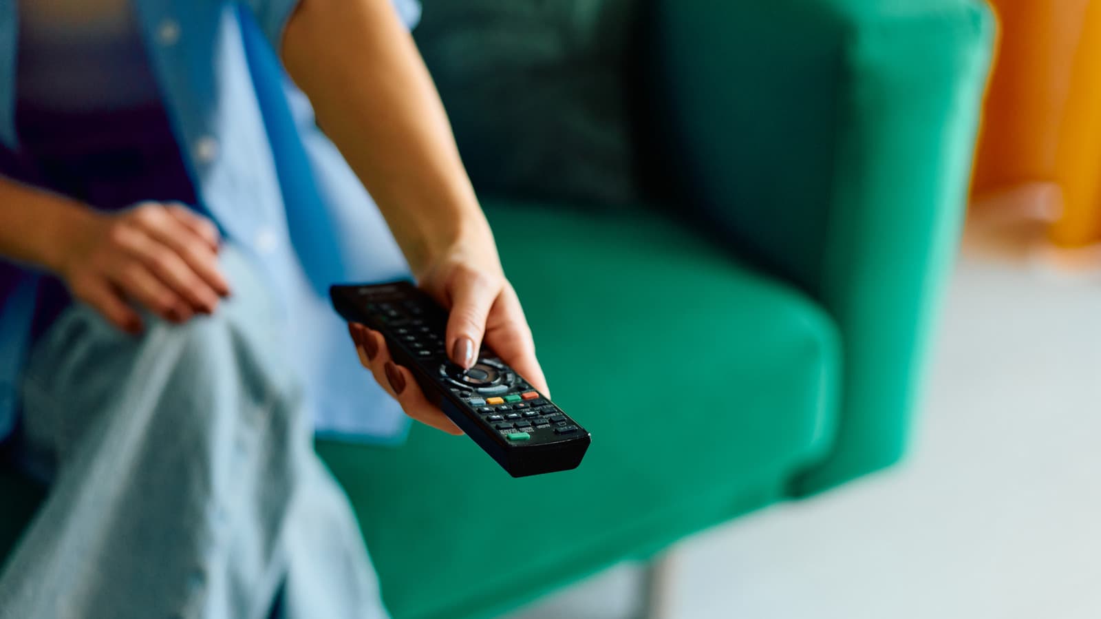 Close-up of a standard TV remote control with many rubber buttons next to a sleek streaming stick remote