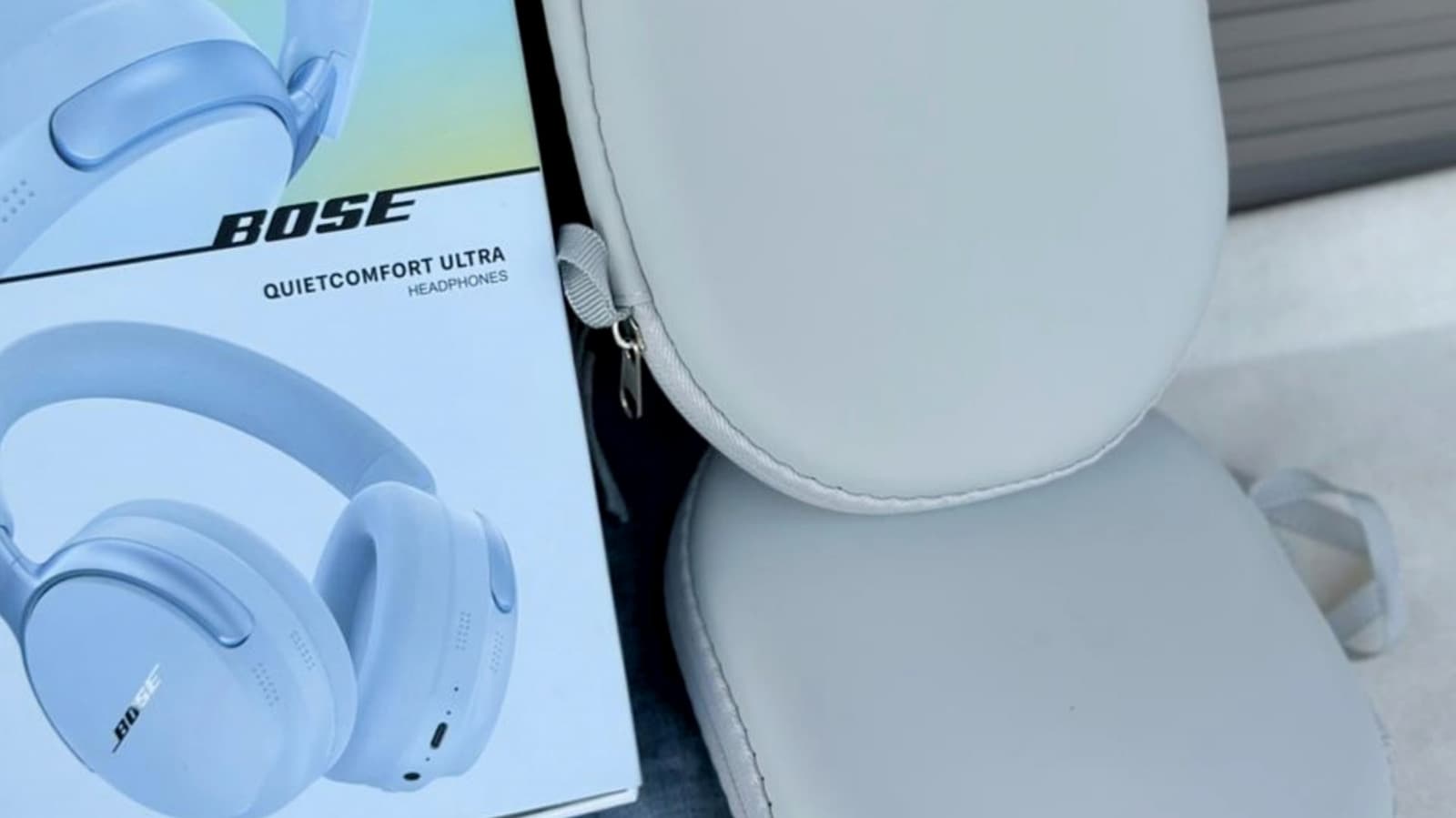 A pair of Bose QuietComfort noise-canceling headphones resting on a wooden desk next to a coffee mug