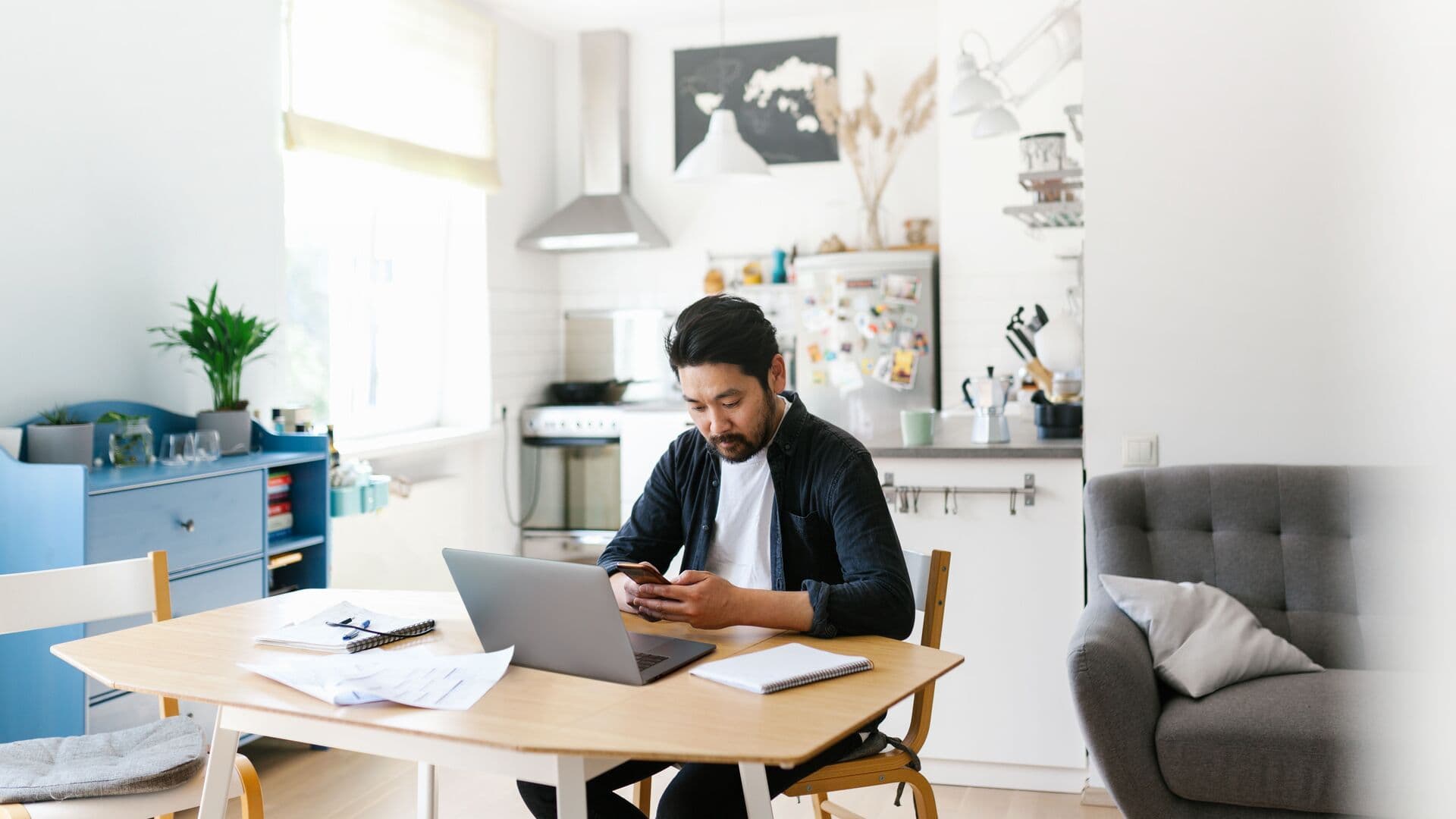 UK small business owner reviewing financial documents while using software on a laptop