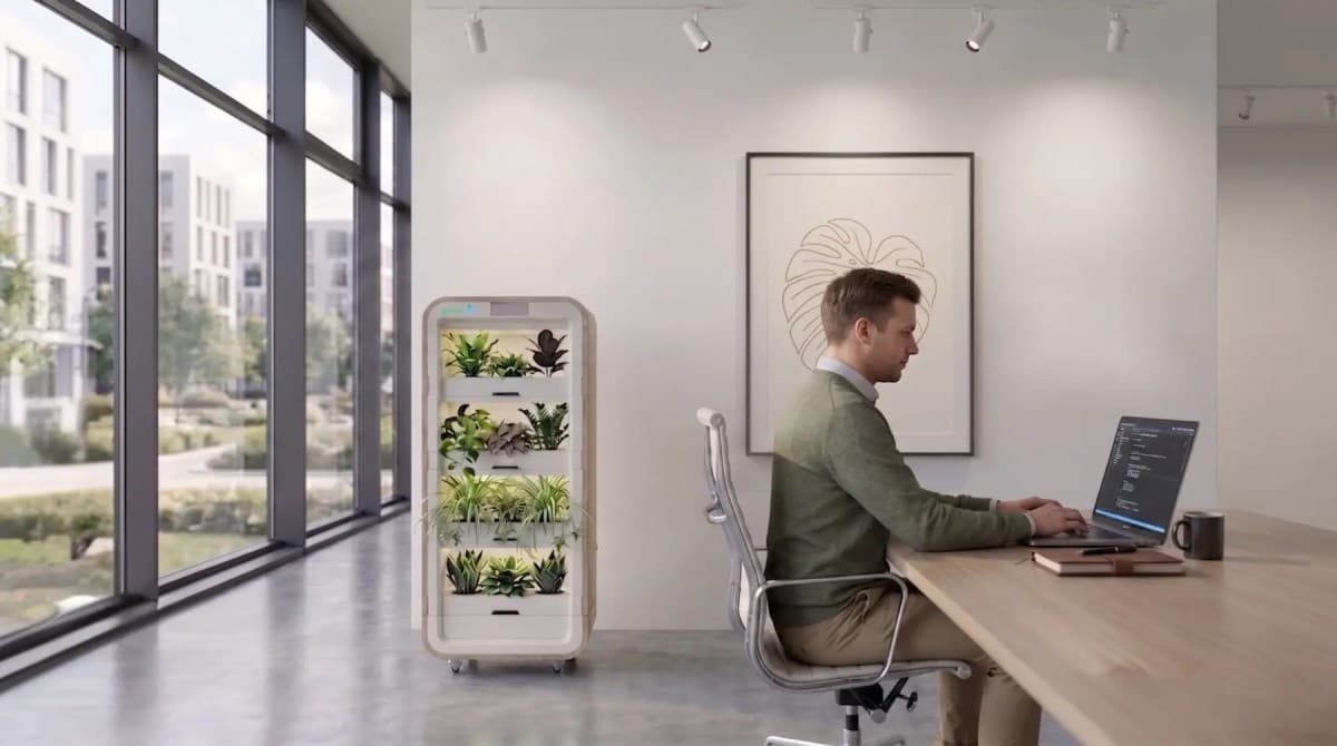 A vertical green plant tower with integrated sensors and LED lights in a modern office setting