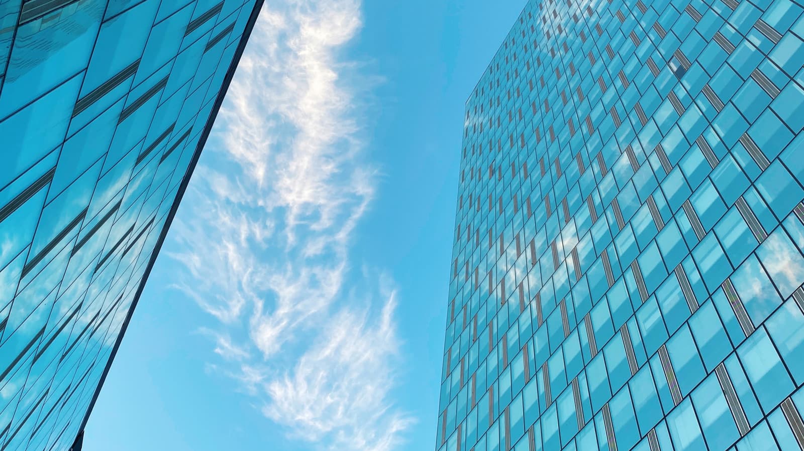 Close-up of a modern high-rise building with transparent glass windows reflecting sunlight.
