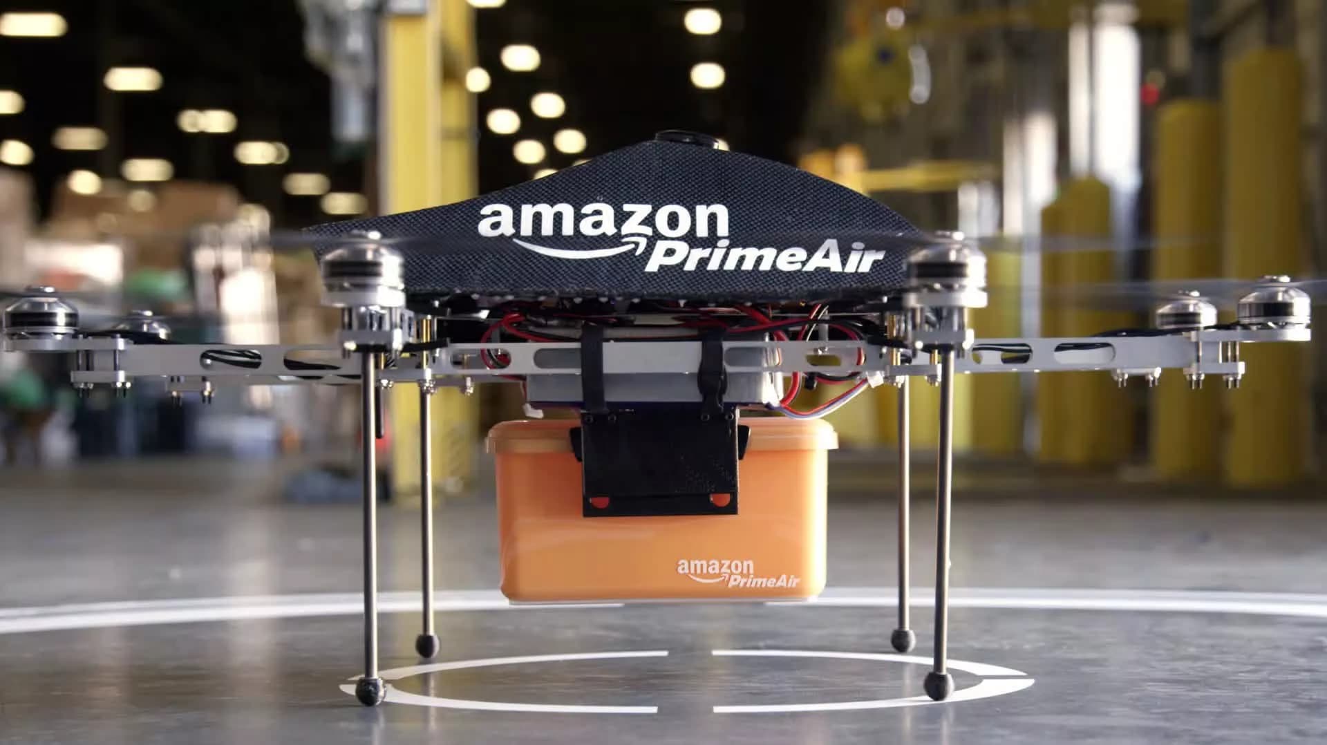 Amazon delivery drone flying over a residential neighborhood with a package underneath