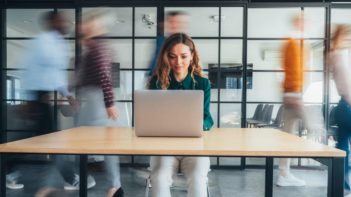 Office workers collaborating with digital AI agent interfaces on screens in a modern workplace setting