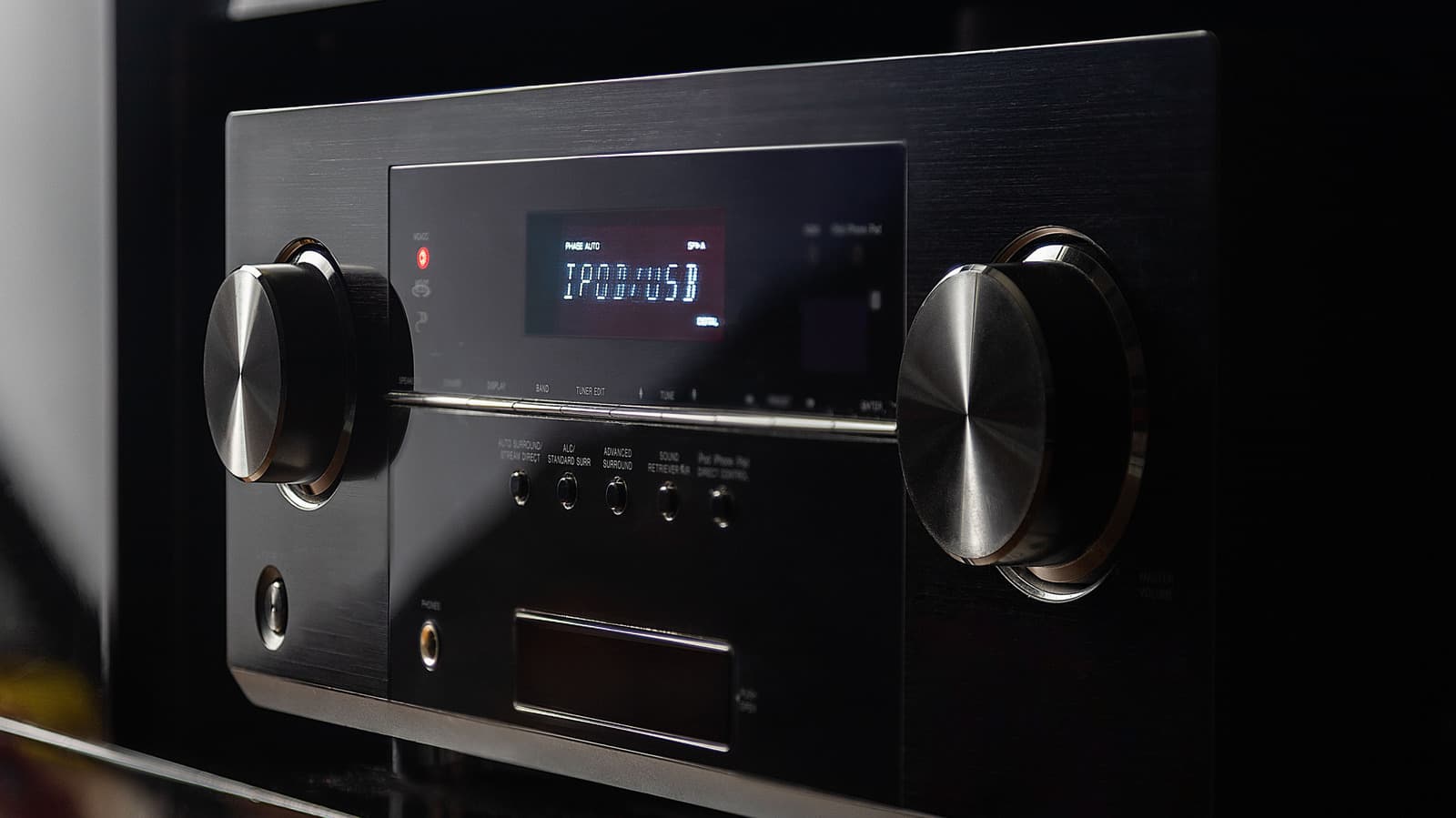 Close up of an AV receiver front panel with knobs and display, home theater setup