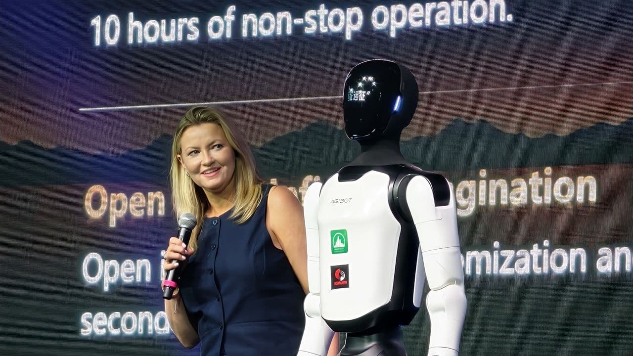 Agibot A3 and X2 humanoid robots on stage at UK launch event performing a dance routine