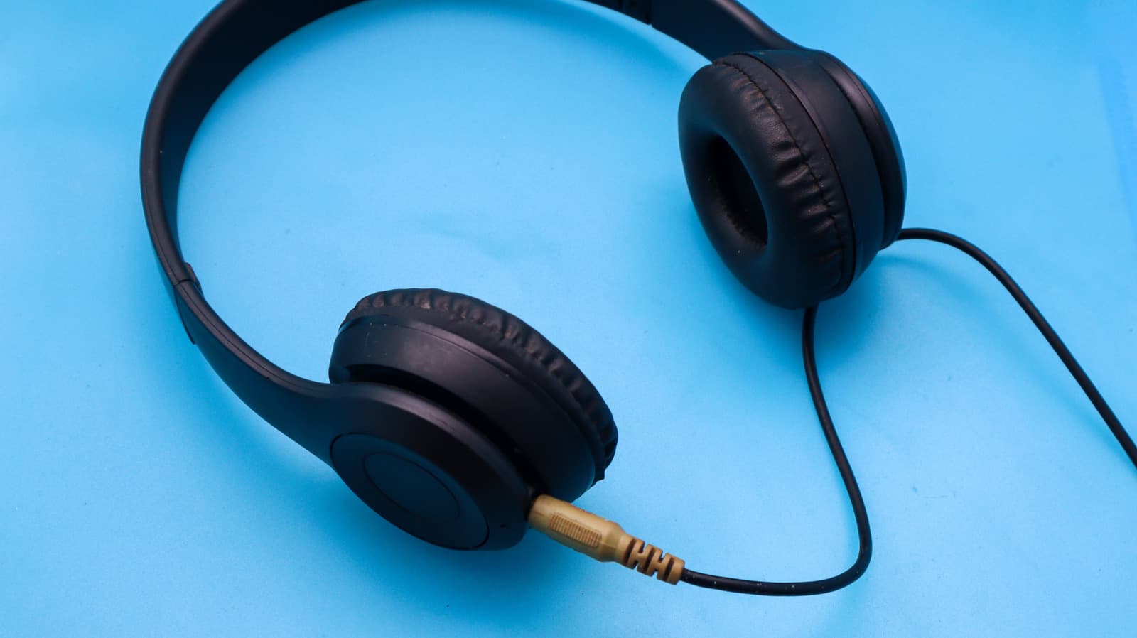 A pair of wired headphones with a braided cable resting on a wooden desk