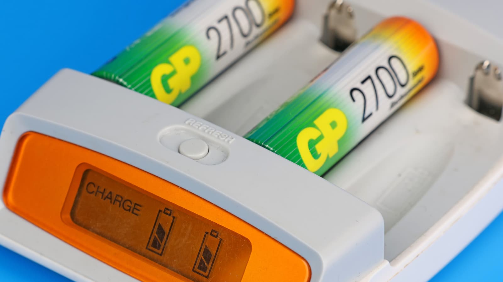 Close-up of a rechargeable AA battery with a charger in the background