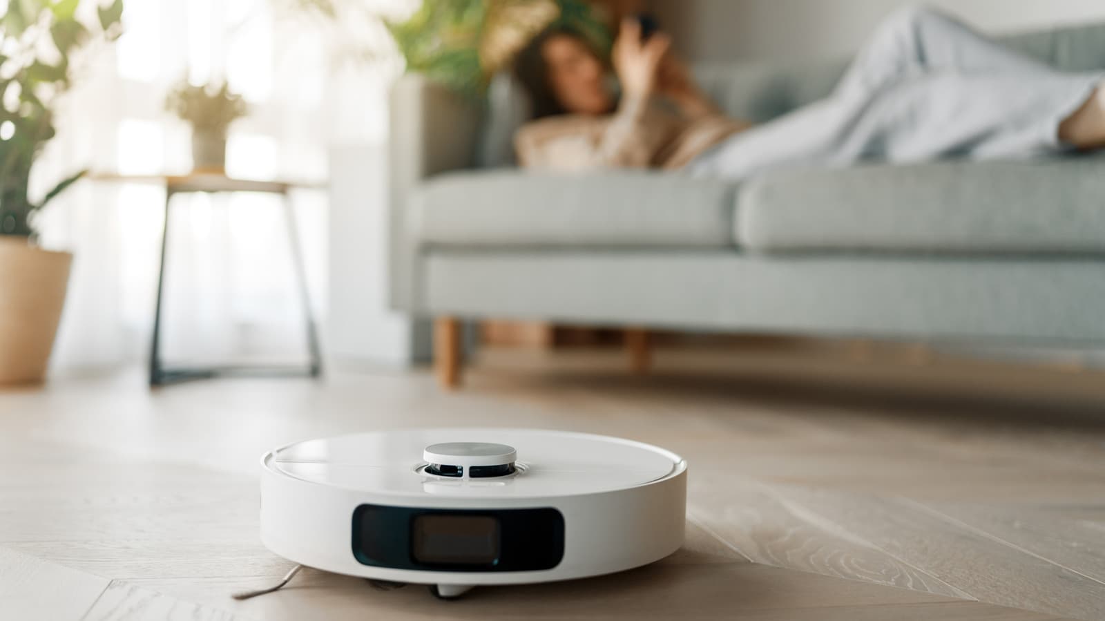 A modern robot vacuum with sensors and a self-emptying base in a living room setting.