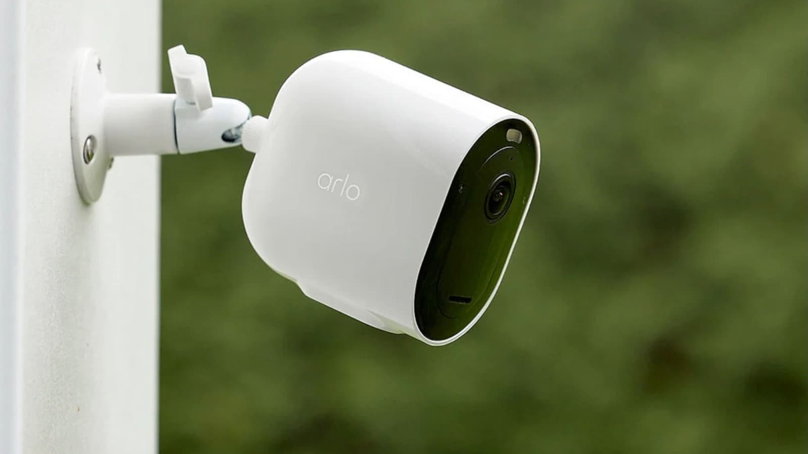 An Arlo security camera mounted on a wall overlooking a driveway