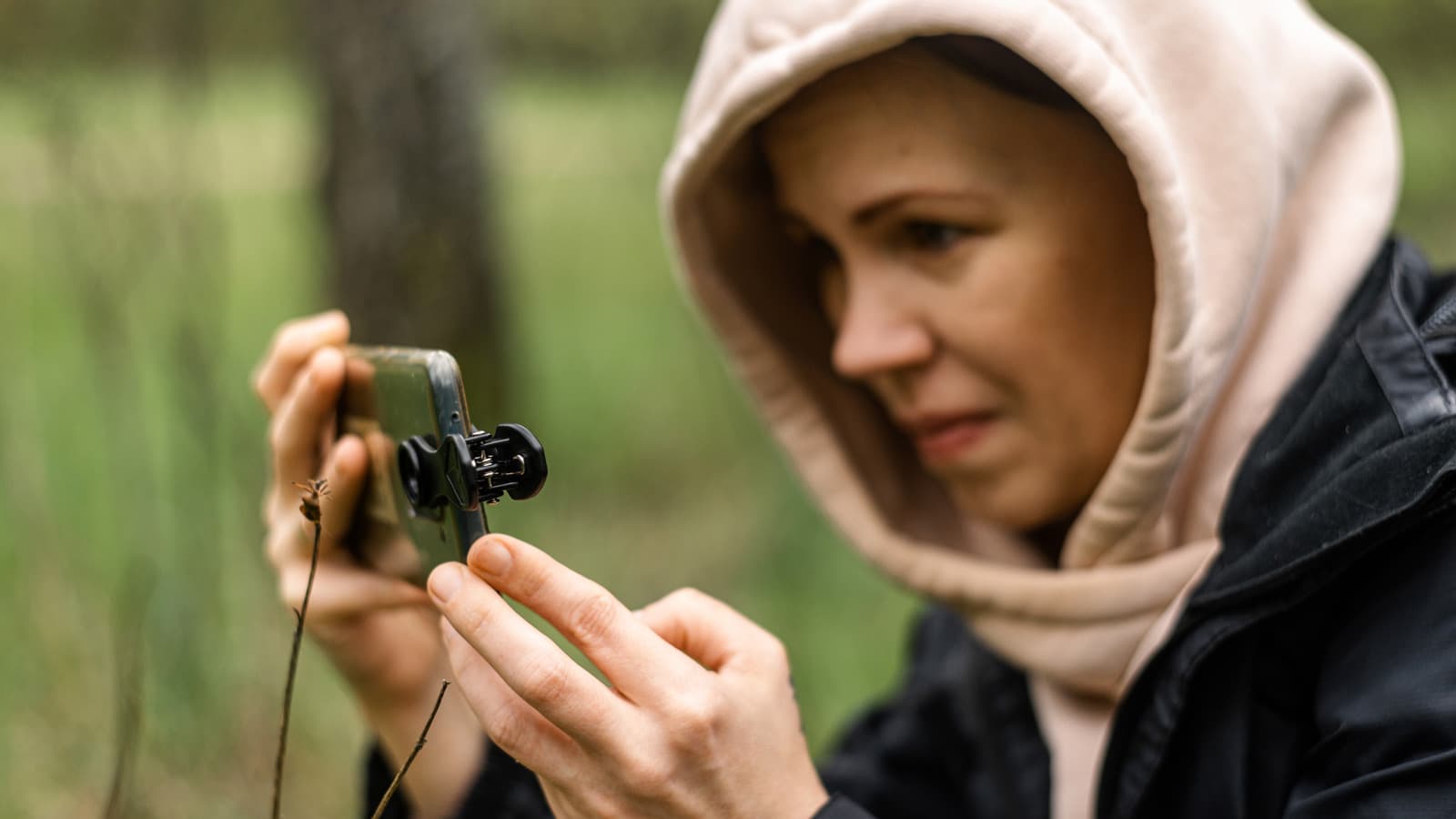 A clip-on camera lens attached to an Android smartphone on a white surface