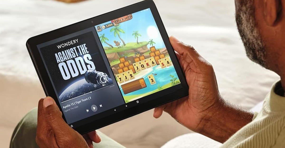 A person holds the Amazon Fire HD 10 tablet in two hands while multi-tasking on screen.