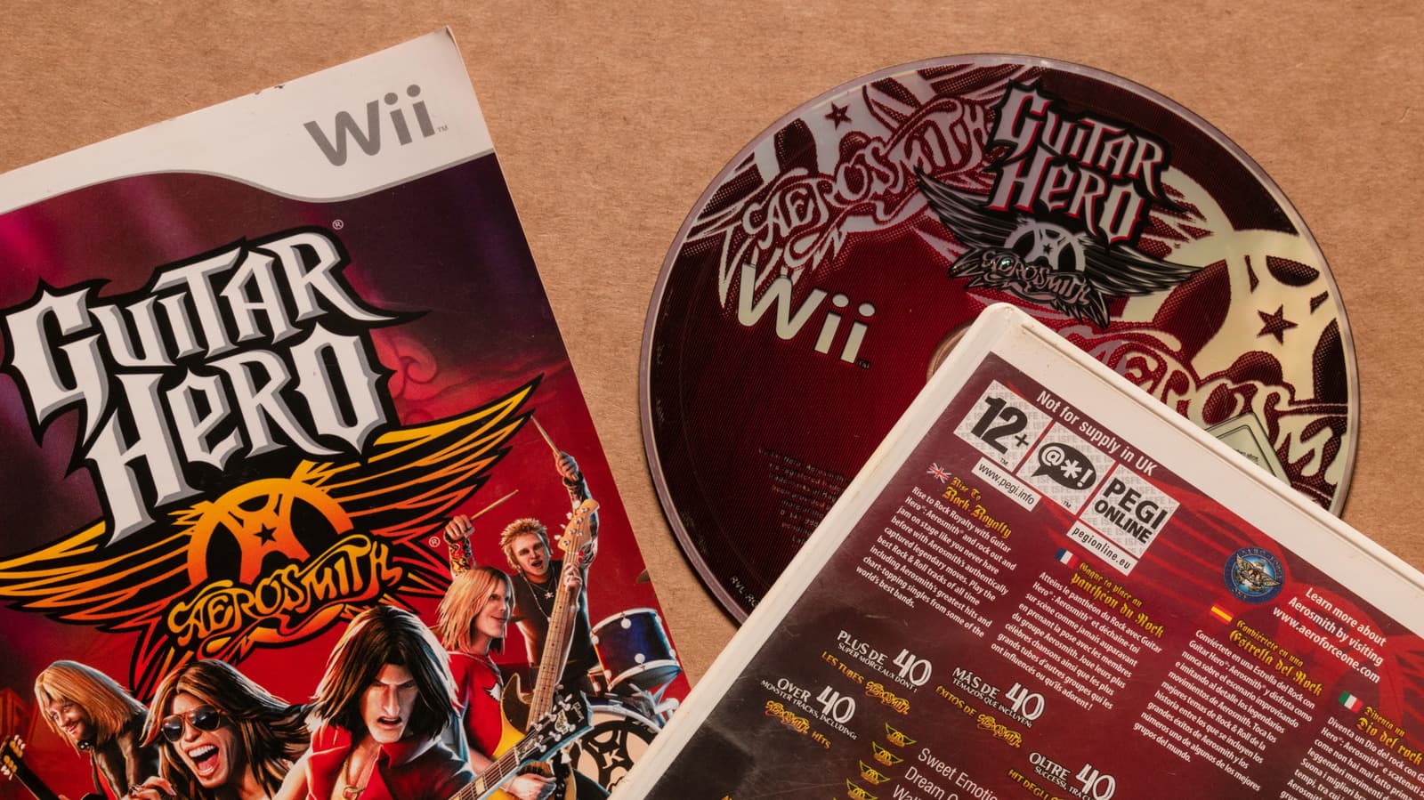 Close-up of a scratched game disc on a shelf with other game cases in background, showing physical media collection