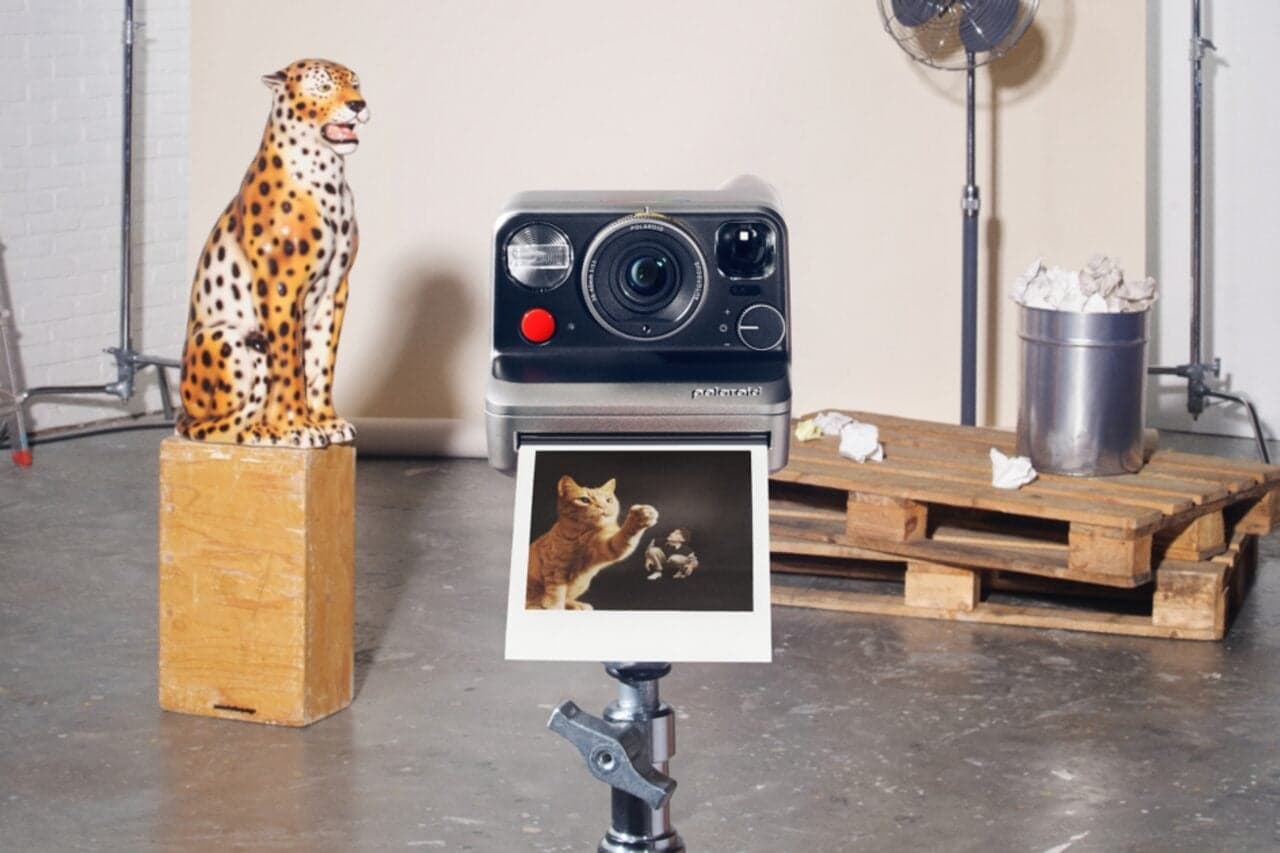 Polaroid Mod instant camera held in photographer's hands showing manual exposure dial and Polaroid film cassette