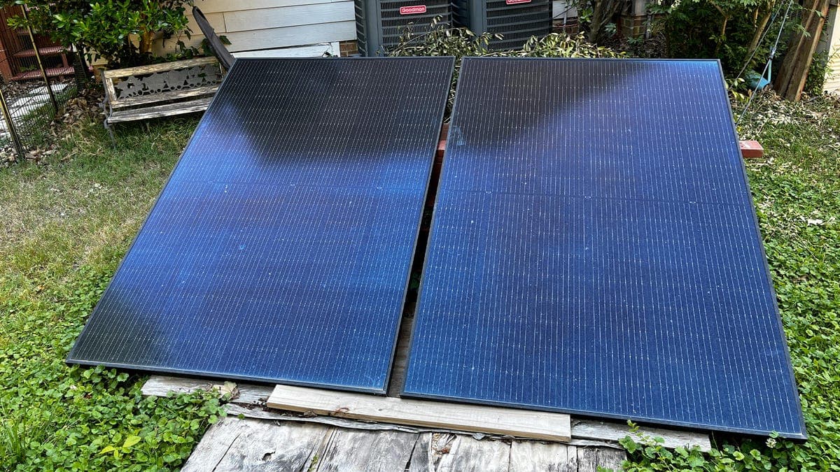 A plug-in solar panel kit connected to an outdoor outlet near a home