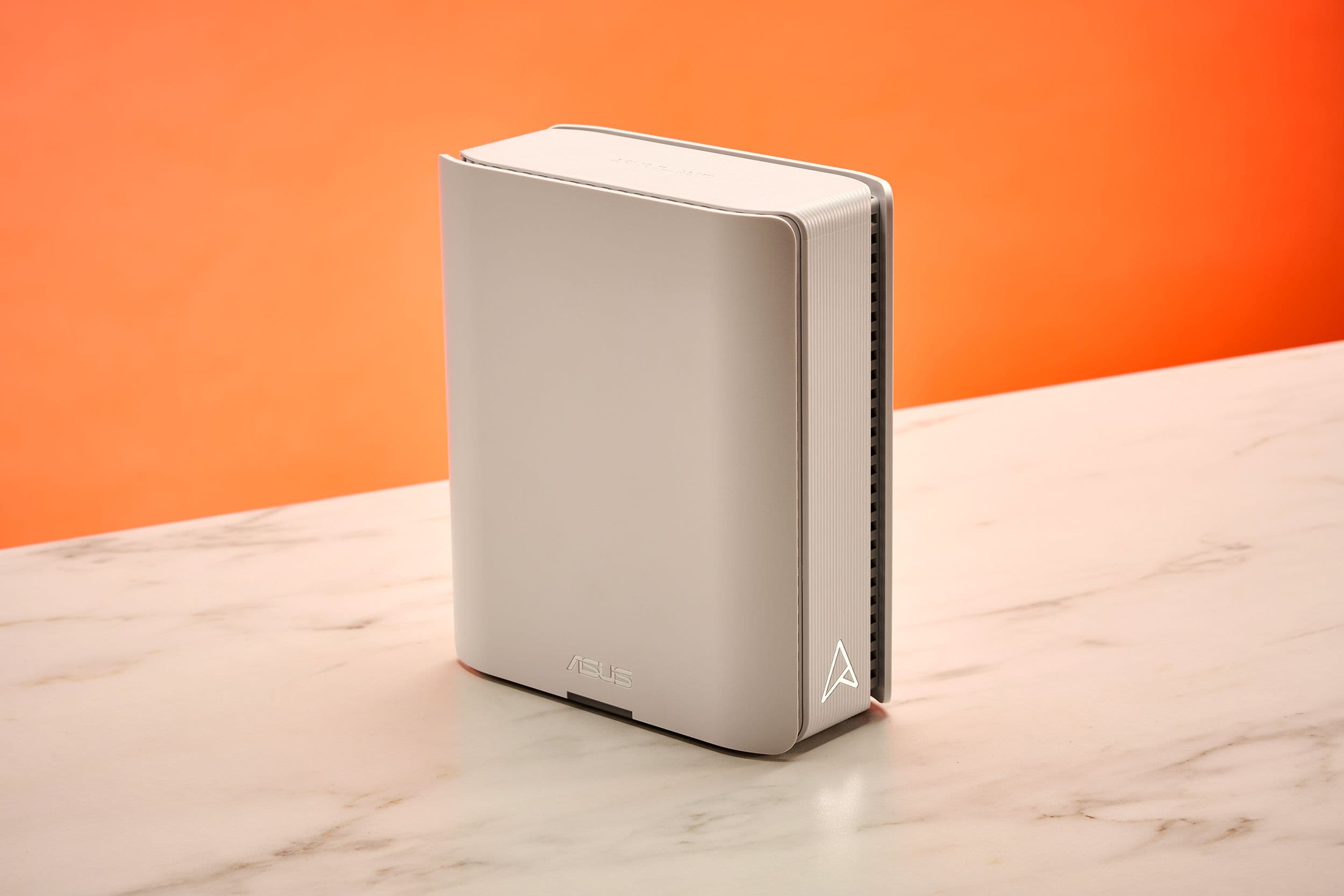 White Wi-Fi router on a desk with antenna pointing upward next to a laptop