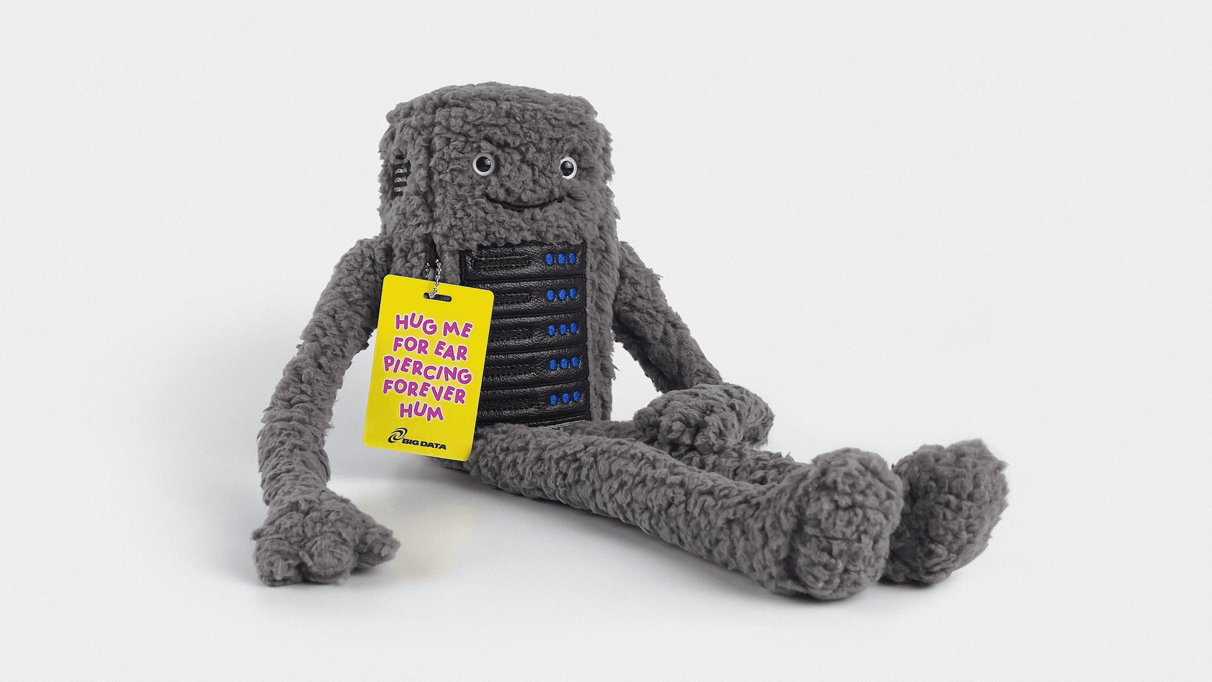 A small round plushie with a neutral expression sits on a desk, representing the Bezzy data center sound toy.