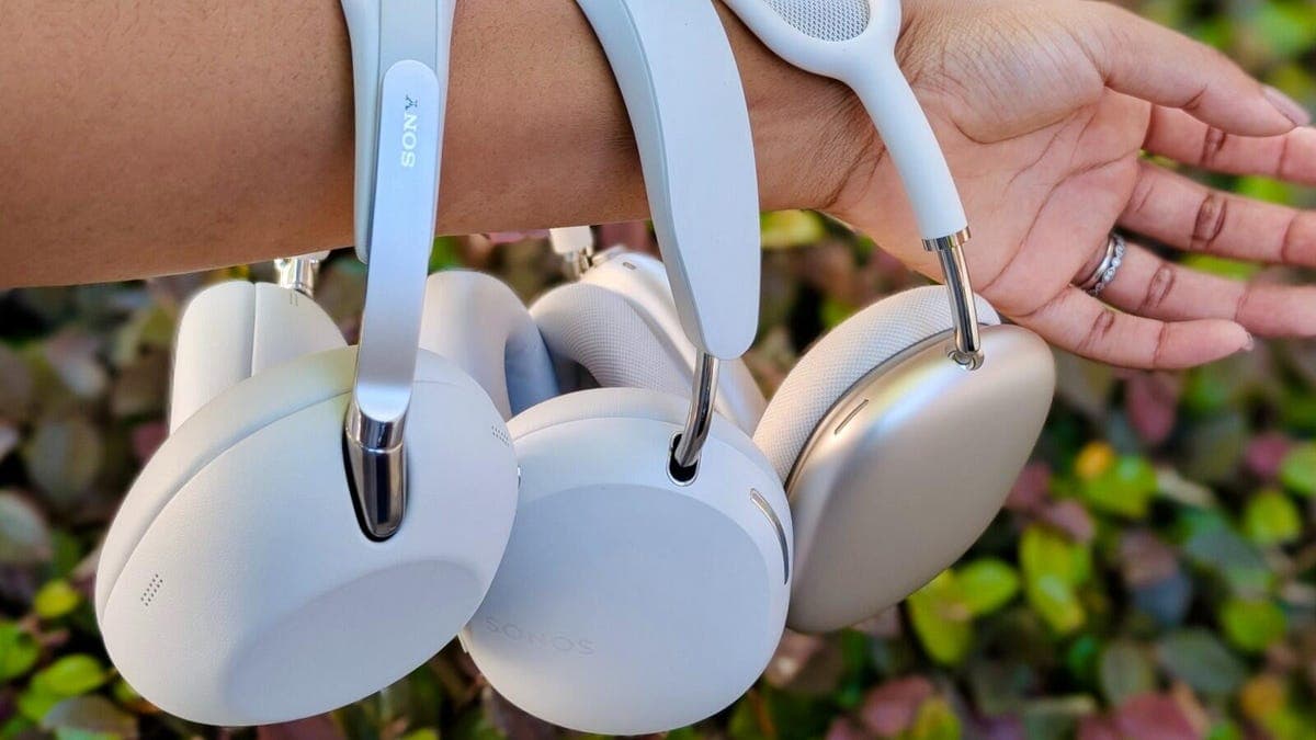 Three premium over-ear headphones on an airplane tray table during flight