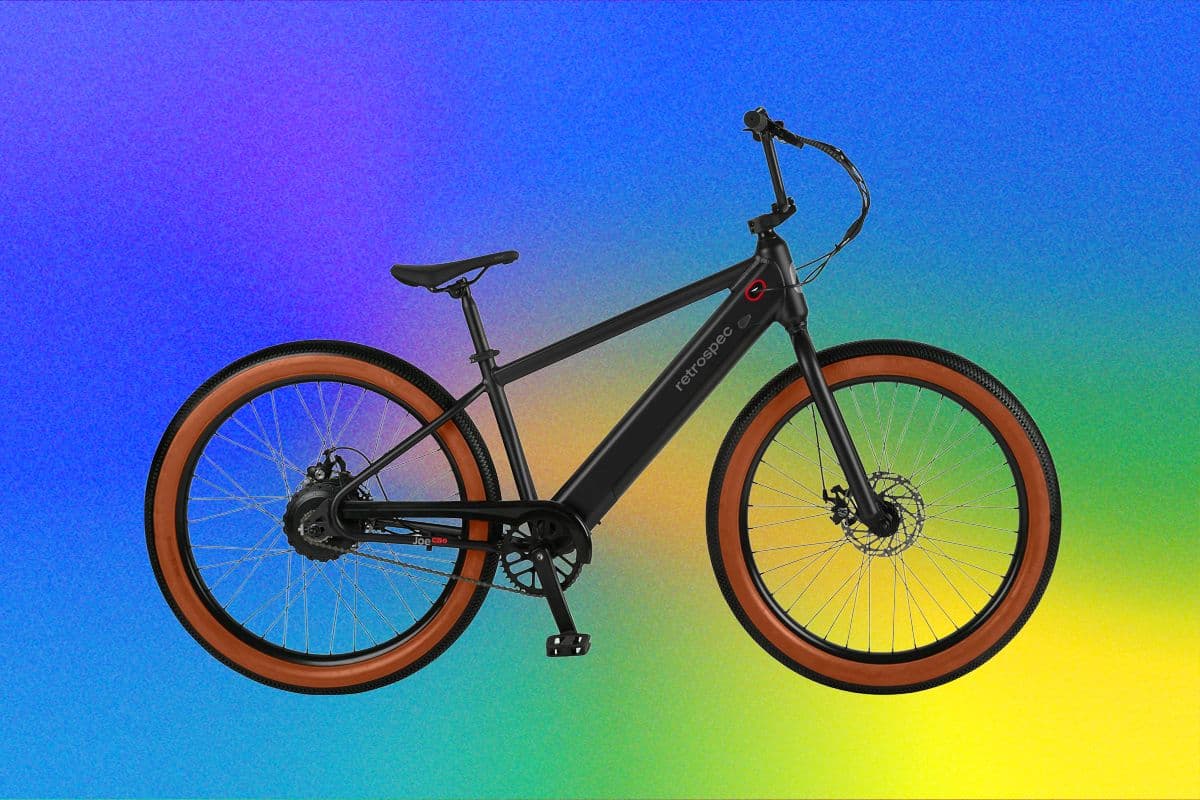 Retrospec Joe Rev 2 electric BMX bike on a paved path with a rider in the background