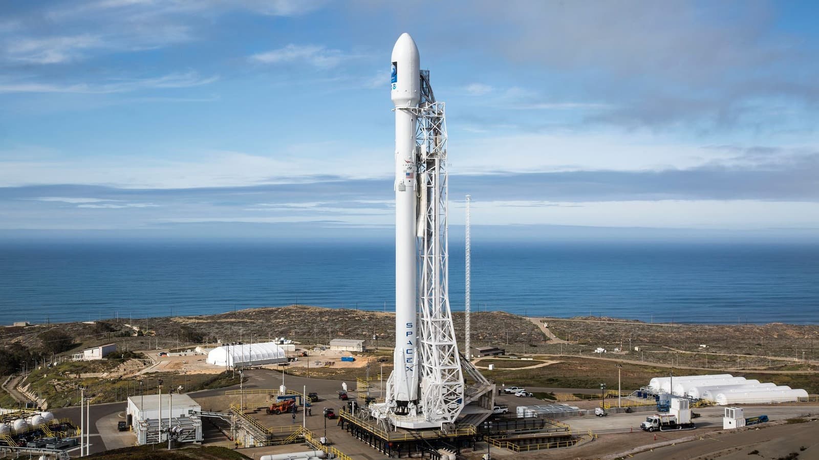 A Falcon 9 rocket launches into space at sunset with the SpaceX logo visible on the booster.